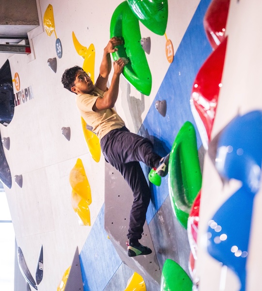 Climber reaching for a hold on a colourful bouldering wall