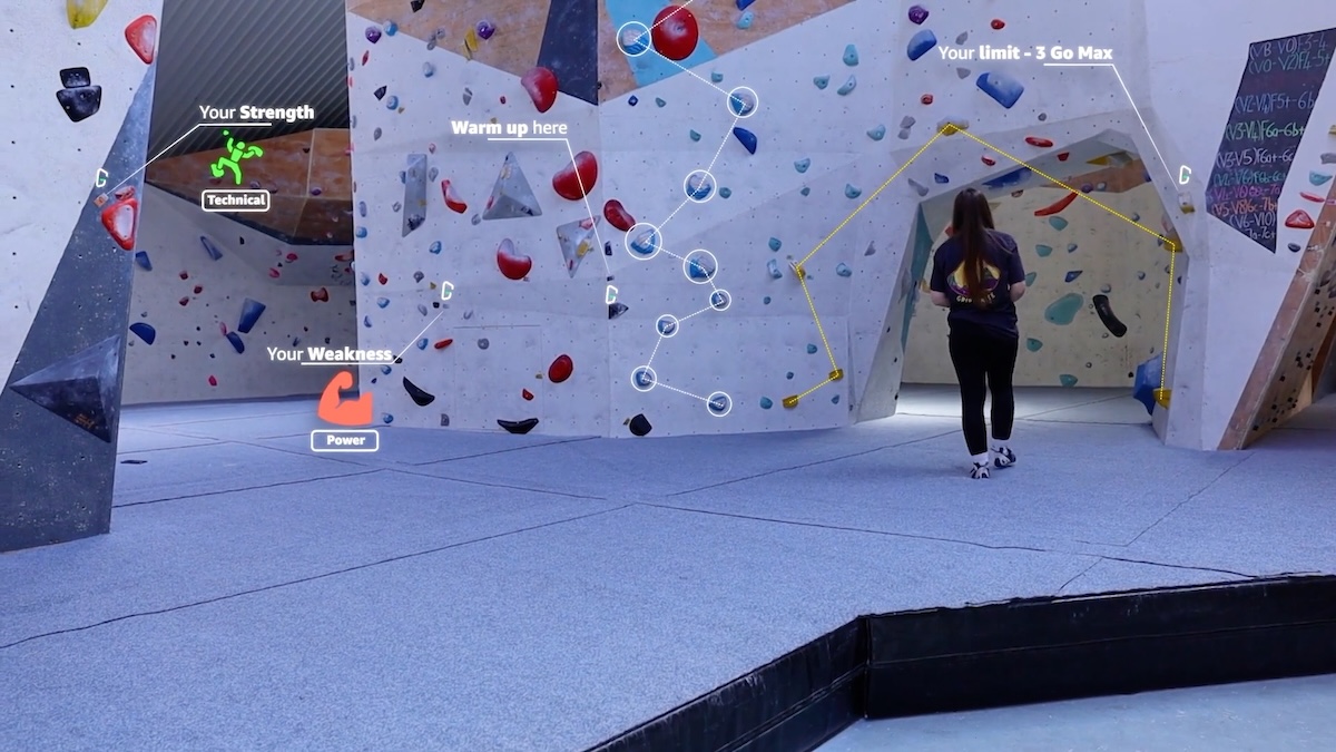 A climber assessing routes on an indoor bouldering wall with Griptonite overlays highlighting recommended climbs