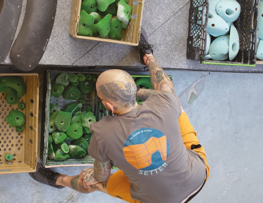 A route setter selects holds from a large bin