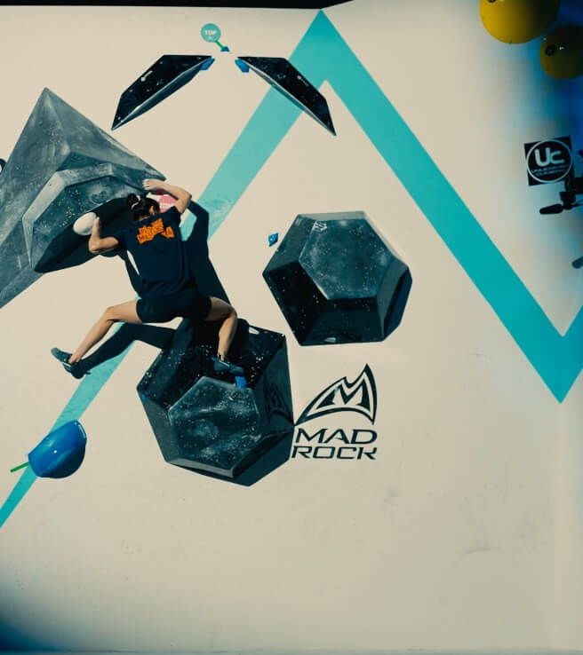 A climber working through a technical sequence on an indoor wall